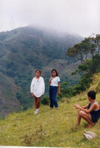 The top of Calumpan Peninsula is flat and grassy. Mount Panay can be seen in the clouds behind.